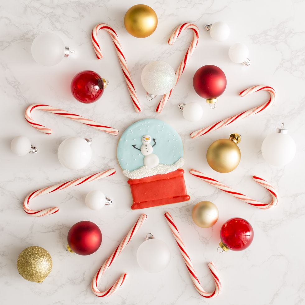 a snow globe christmas cookie surrounded by candy canes and ornaments