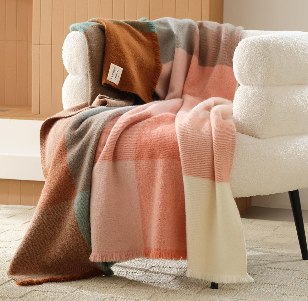 A soft, multicolored blanket draped over a white, textured chair in a cozy room.