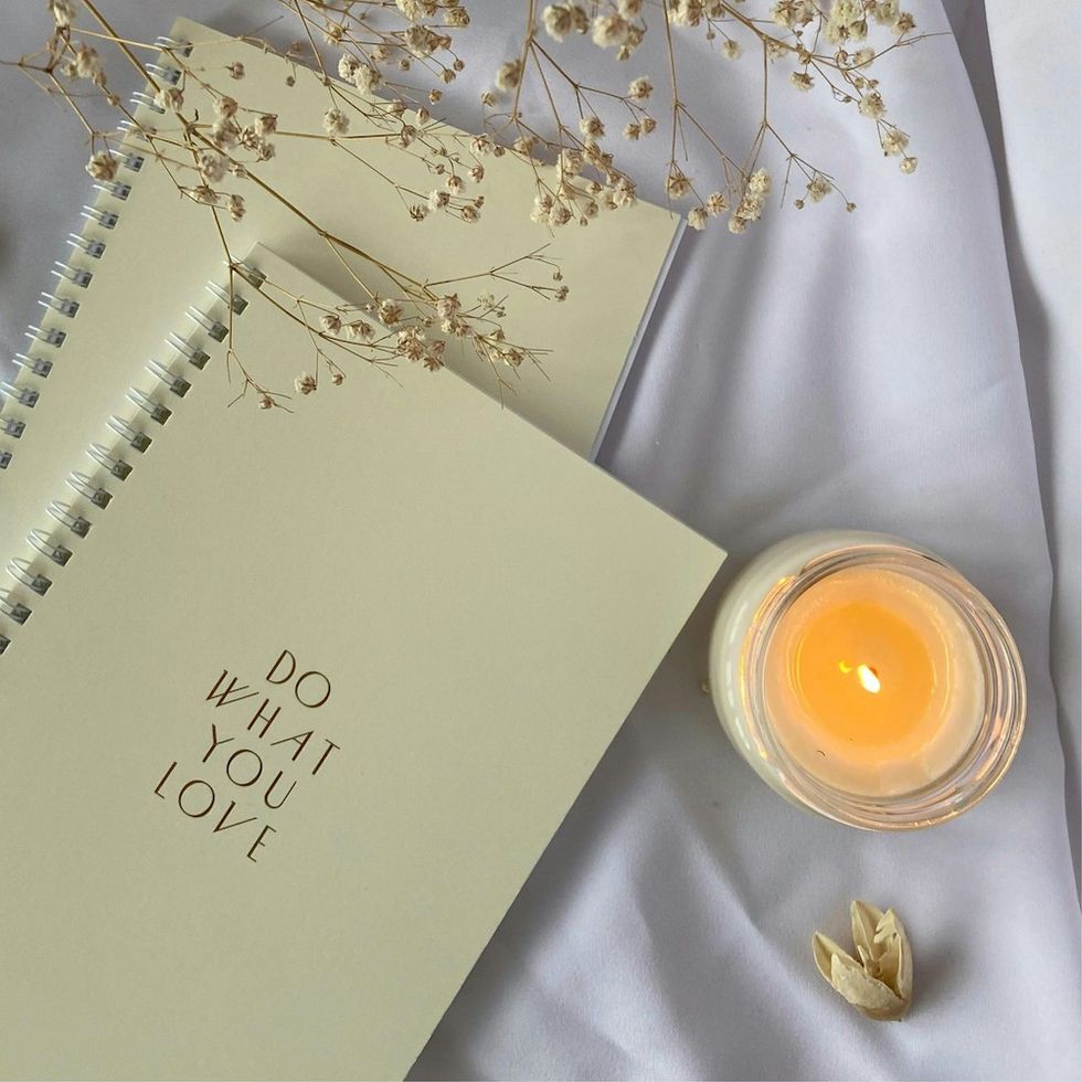 a spiral notebook that says "do what you love" next to a lit candle