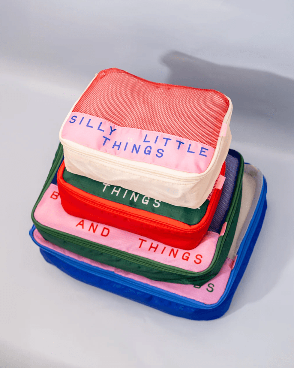A stack of colorful zippered pouches with pink labels and playful text.
