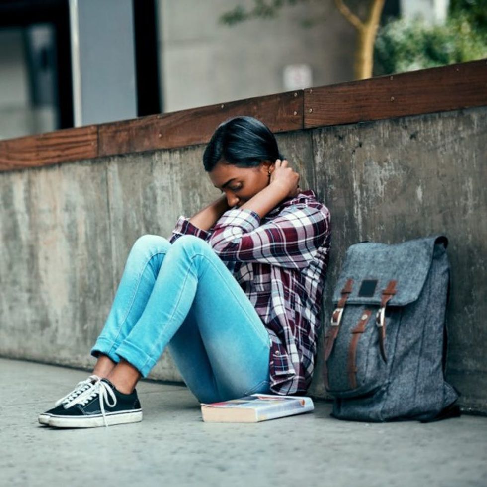 A stressed student sits along a wall