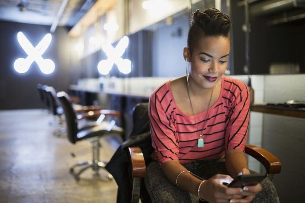 A stylist uses her phone at her salon