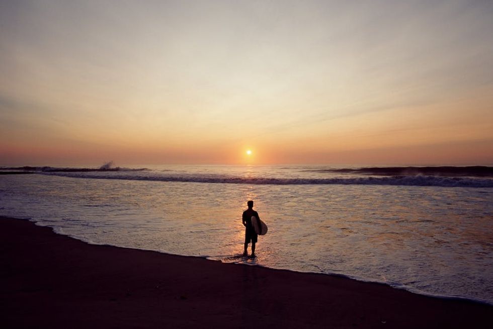 A surfer stands on the shore in Spring Lake to watch the sun rise