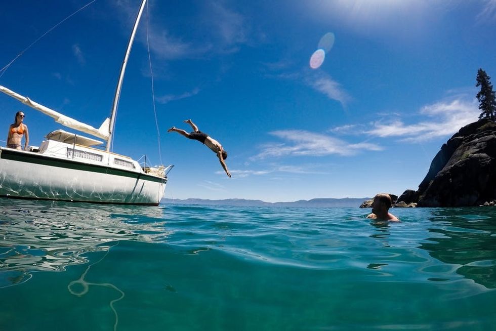 A swimmer dives off the side of a boat into Lake Tahoe's Emerald Bay