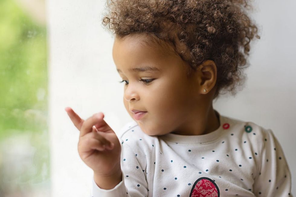 A toddler looks at her hand