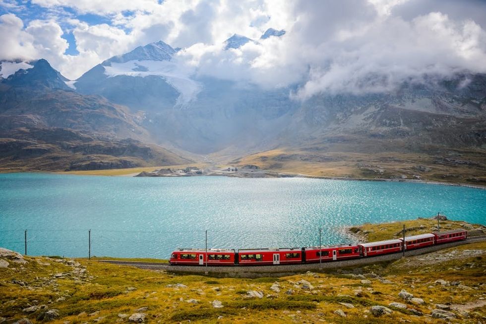 A train runs on the Bernina railway beside Lake Bianco