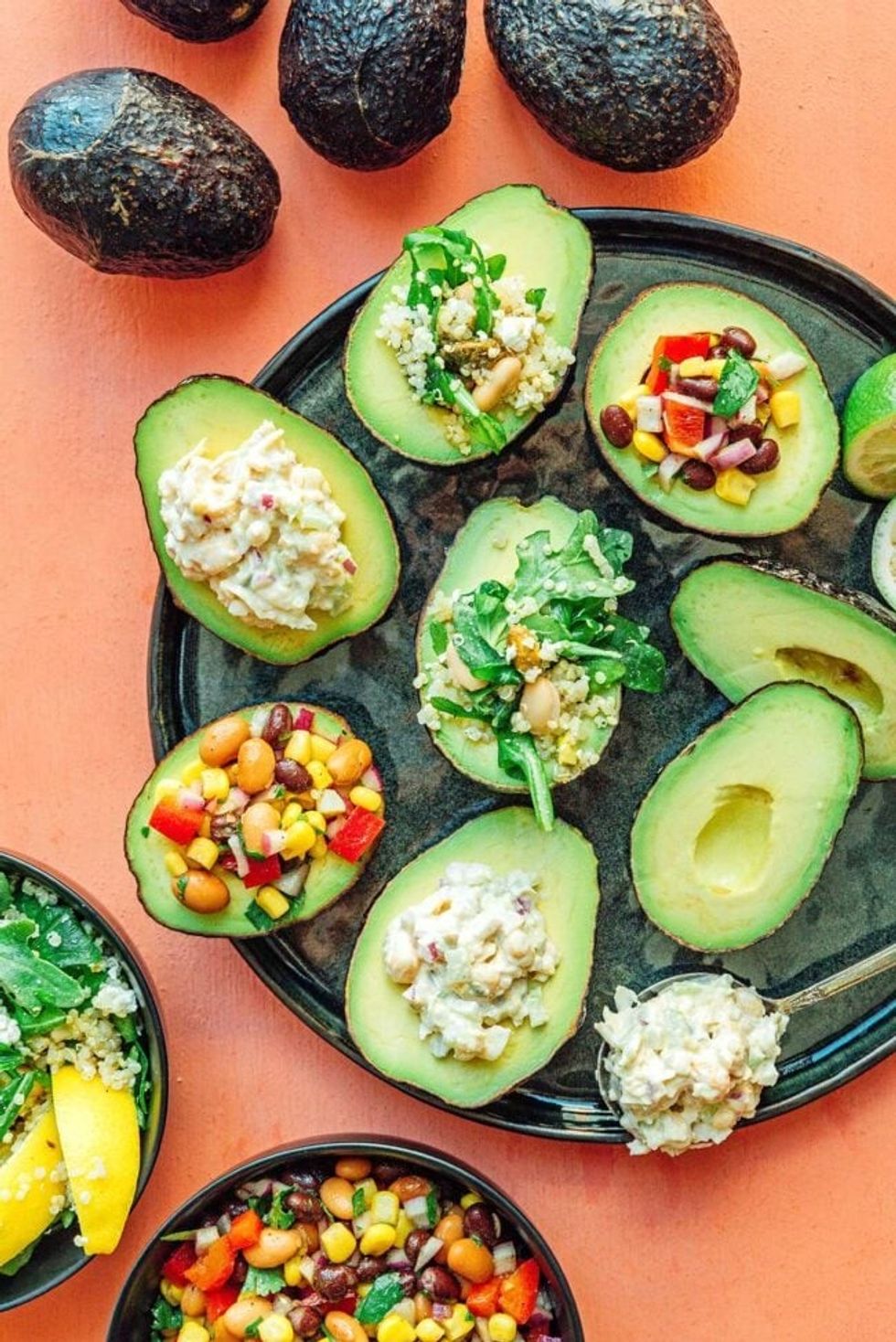 A tray of stuffed avocados sits on an orange table.