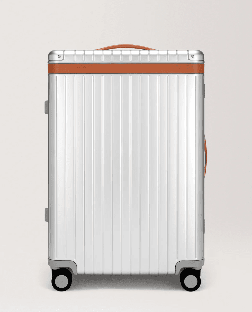 A white ribbed hard-shell suitcase with orange trim and four wheels.