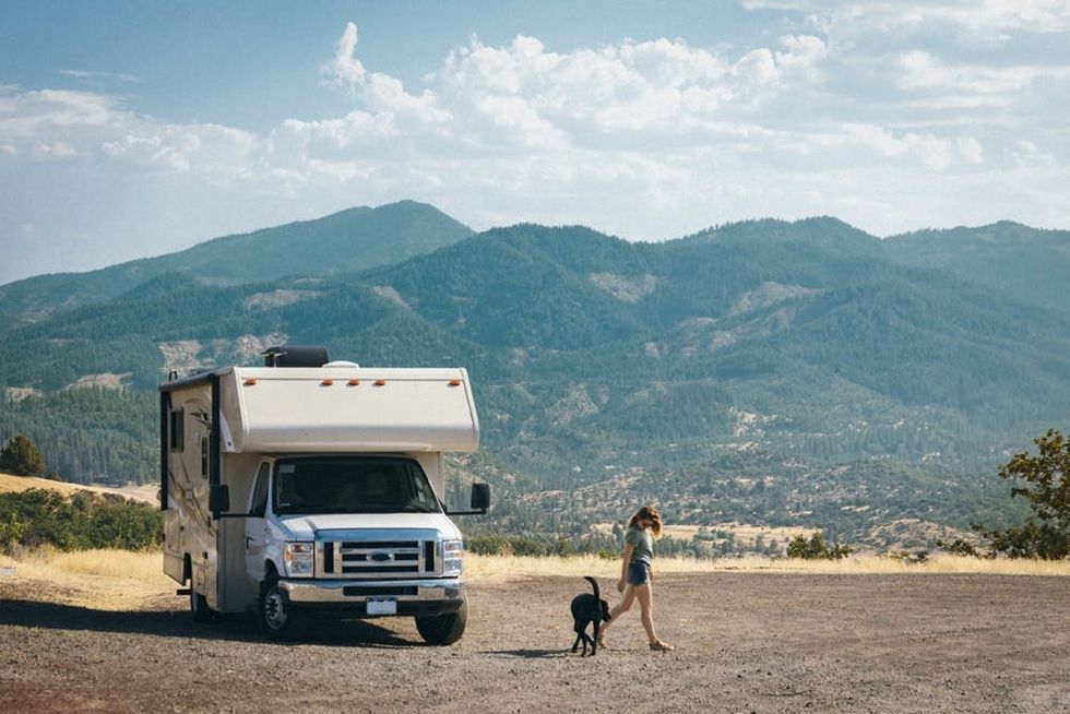 A woman and her dog stretch their legs by her RV