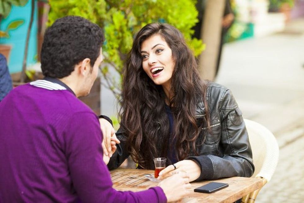 A woman and man hold hands at an outdoor table