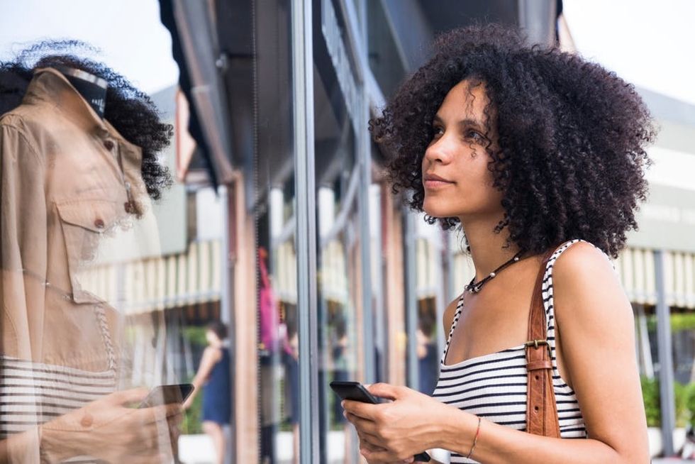 A woman considers an item displayed in a store window