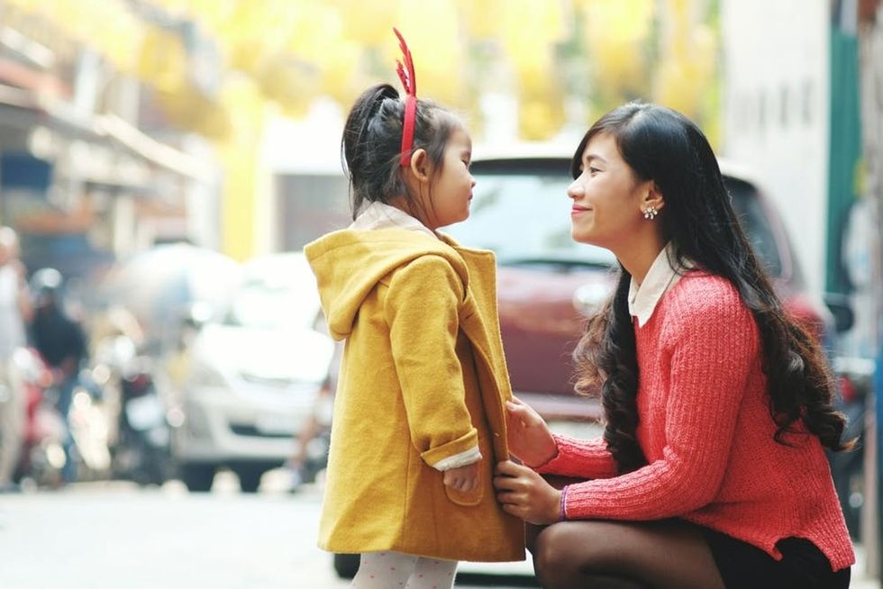 A woman crouches to speak with her child
