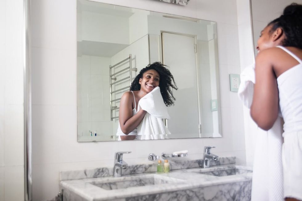 A woman dries her face in front of the bathroom sink