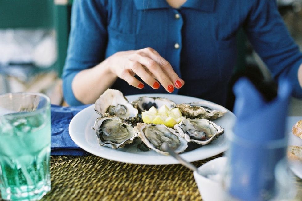 A woman eats fresh oysters by the seaside