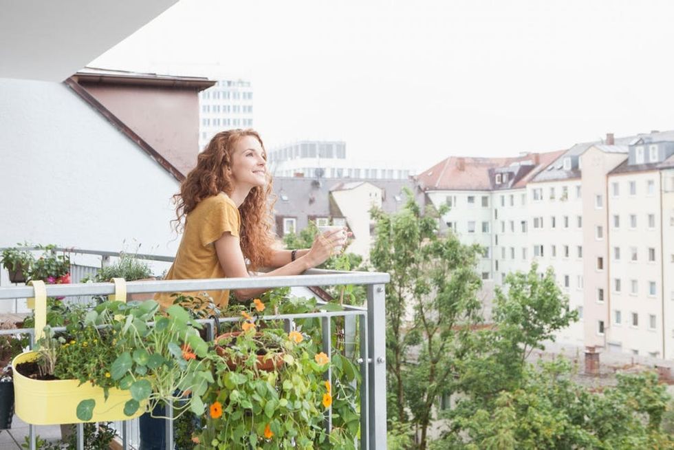 A woman enjoys a cup of coffee on her balcony