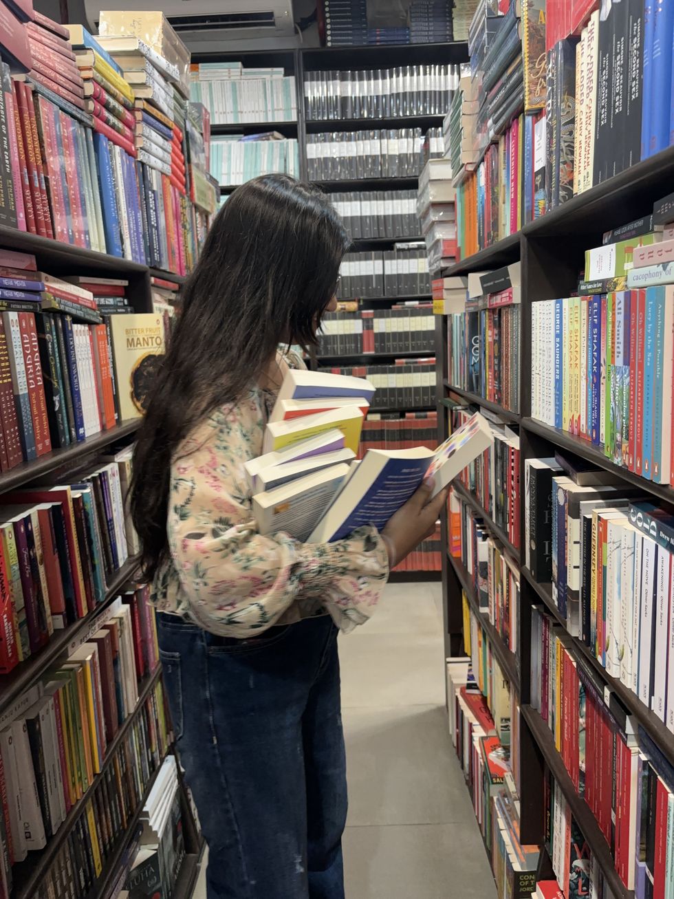 a woman holding a lot of books at a store