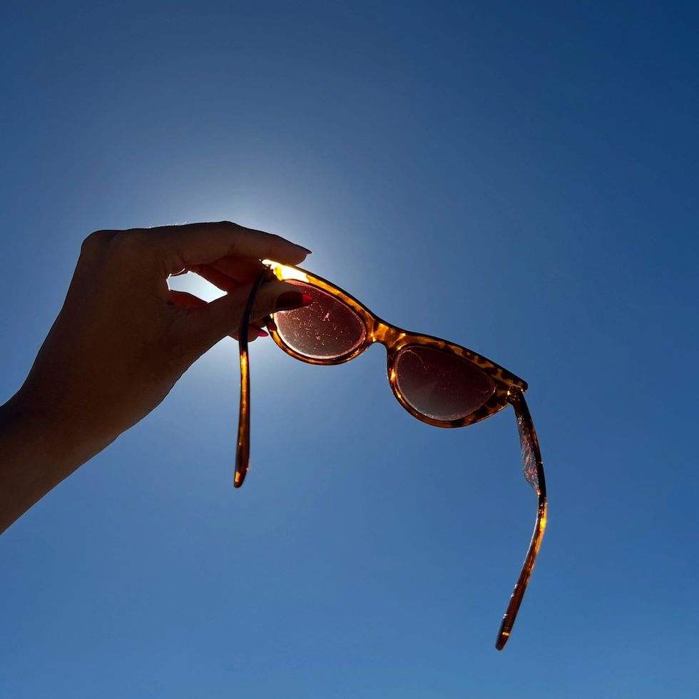 a woman holding up sunglasses