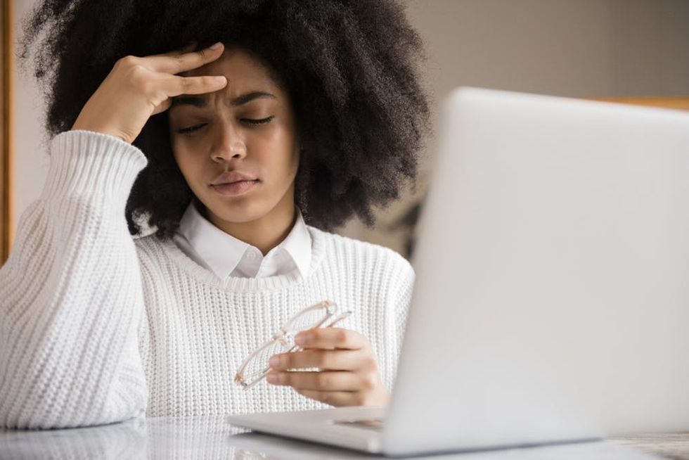 A woman holds her glasses as she rubs her forehead