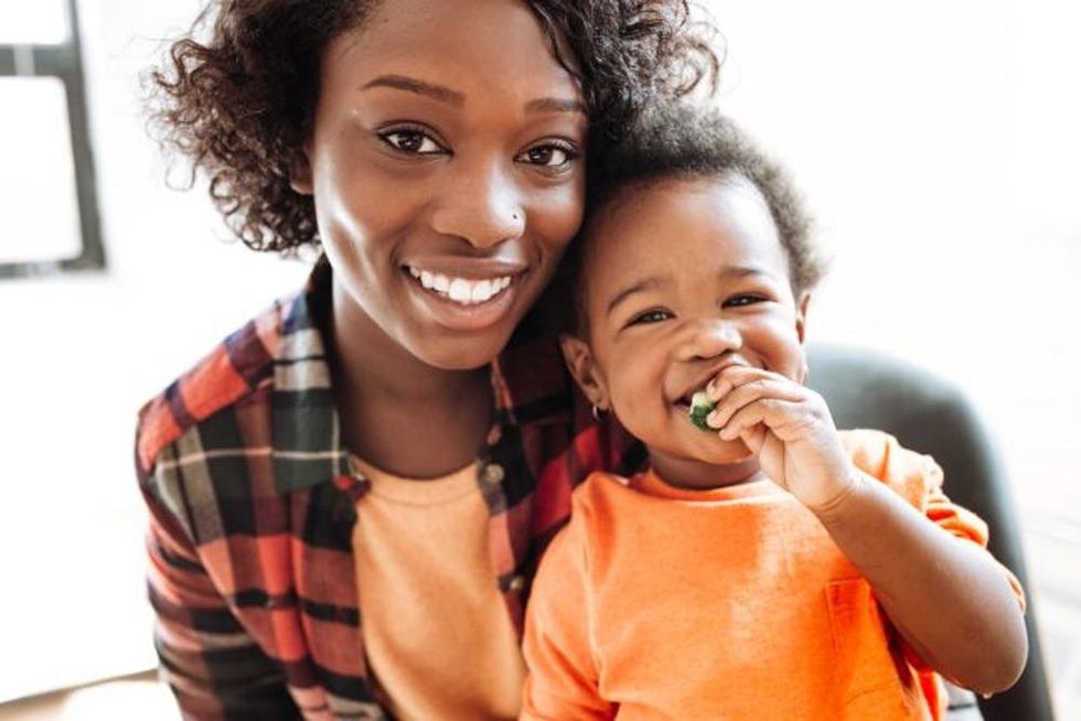 A woman holds her toddler as he eats a snack