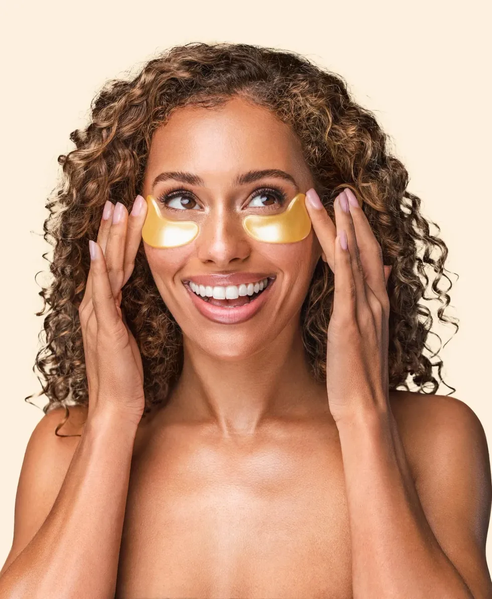 A woman is applying gold under eye masks.