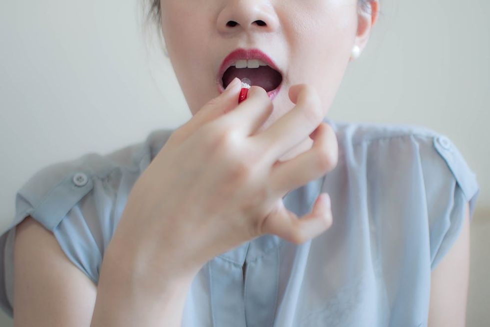 A woman is taking a medicine capsule indoor