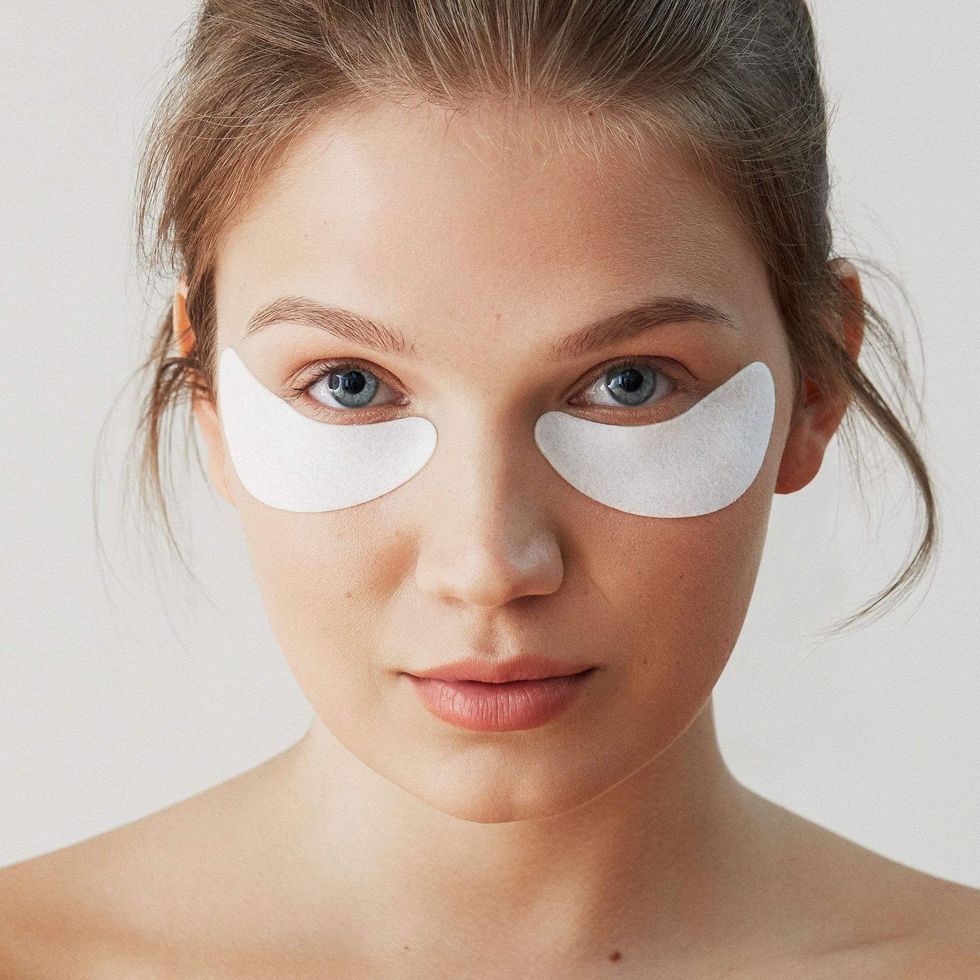 A woman is wearing white under eye patches.