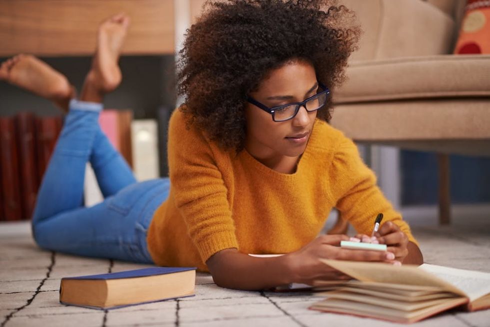 A woman lies on the floor studying
