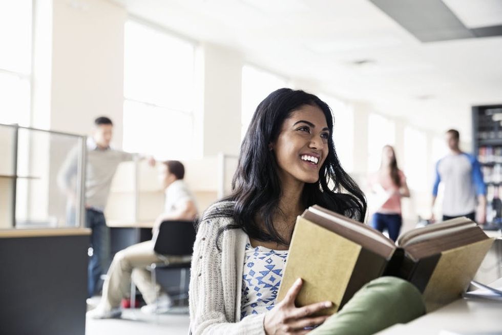 A woman looks up from a textbook and smiles