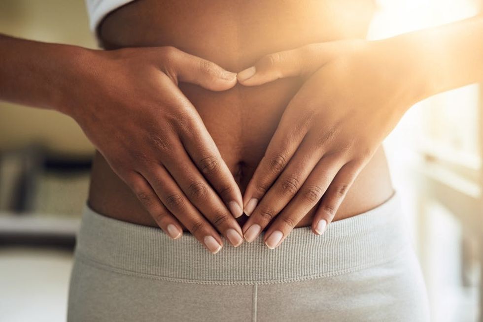 A woman makes a heart shape over her stomach