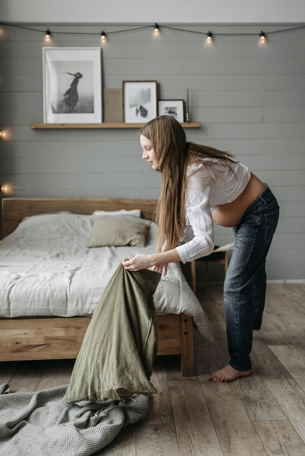 a woman making her bed with her bed sheets