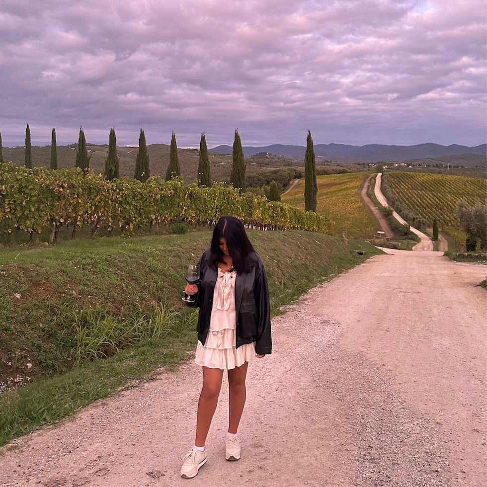 a woman on a path at a vineyard with a glass of wine