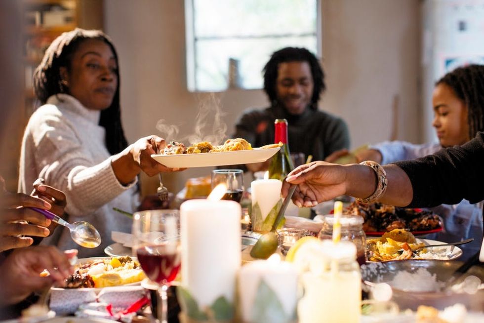 A woman passes a plate of food across the table at a holiday dinner