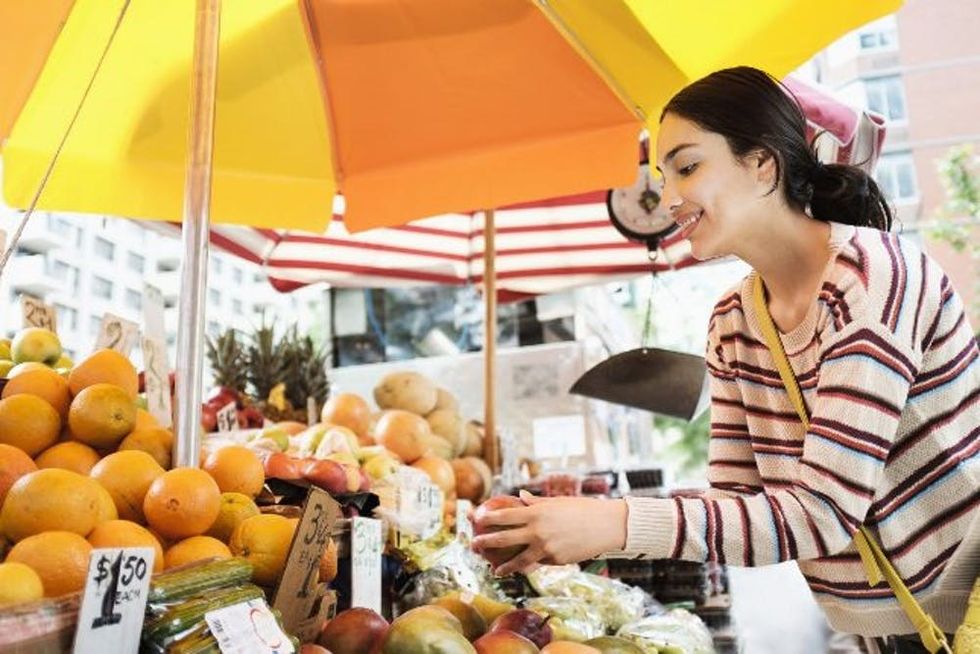 A woman picks out fruit at a farmers' market