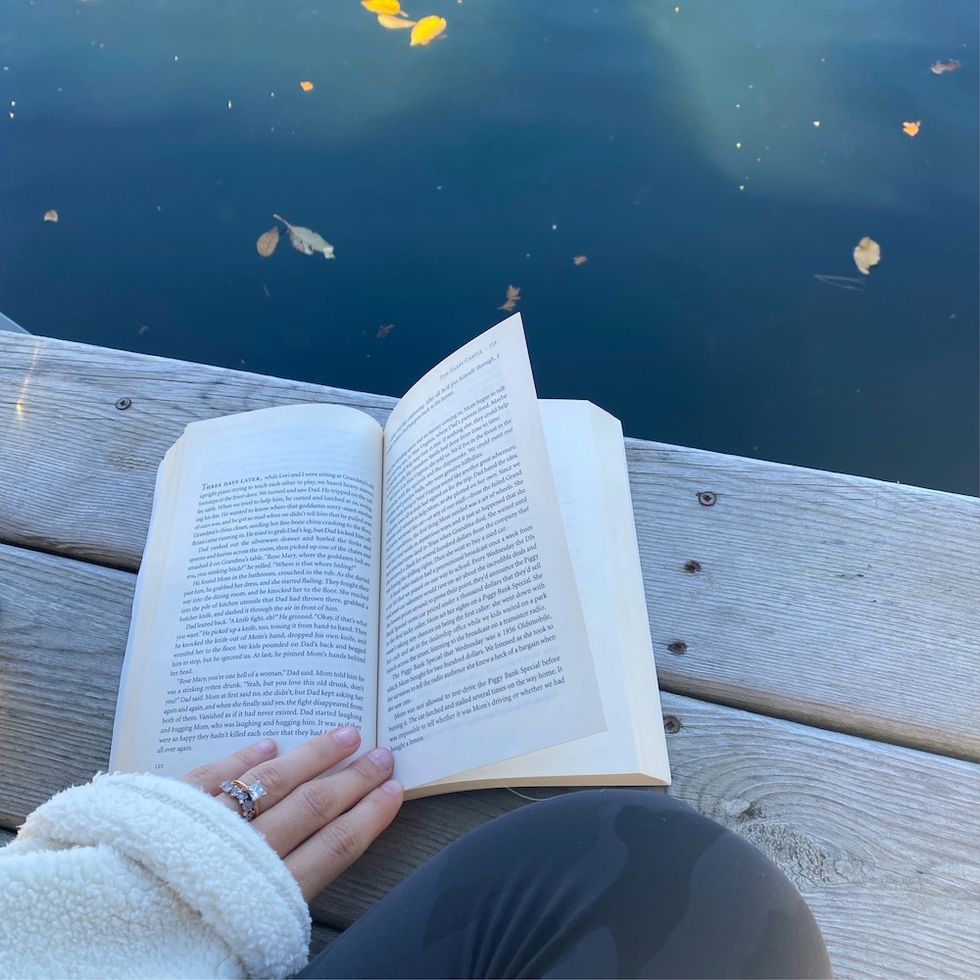 a woman reading a book on the dock