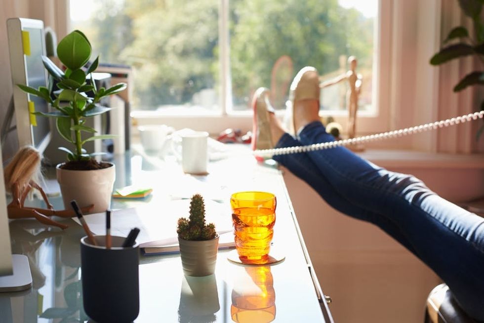 A woman rests her feet on her desk as she talks on the phone