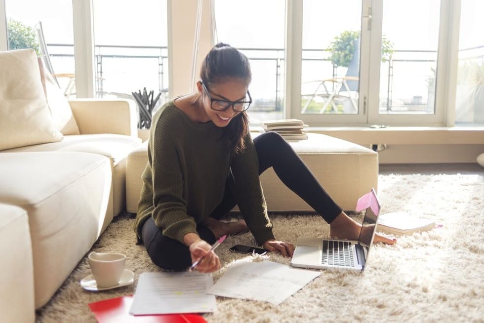 A woman sits and writes on her living room floor