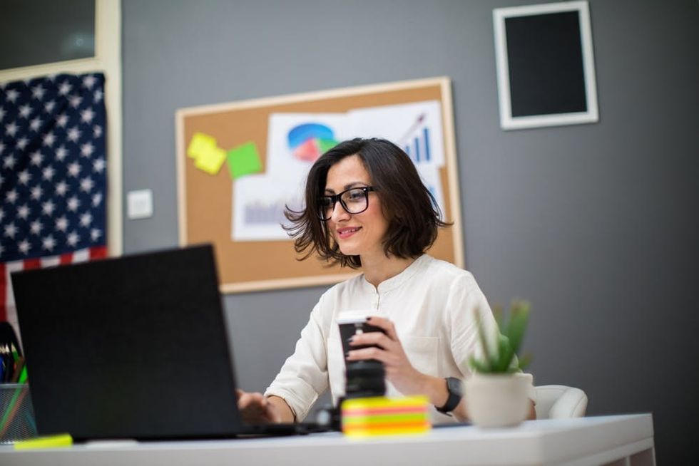 A woman sits happily at her desk