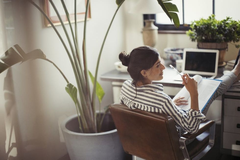 A woman sits with her feet up on her desk in a sunny office