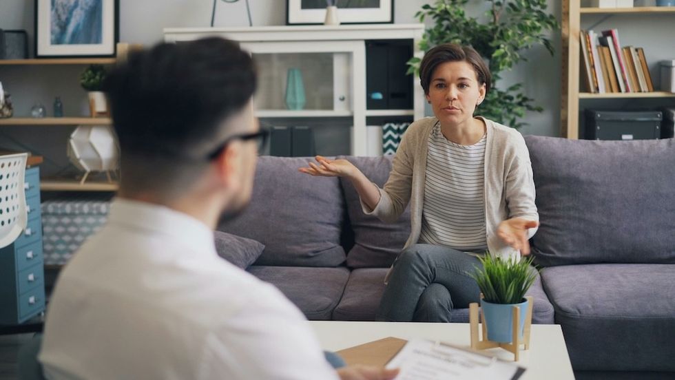 a woman sitting on a couch in the middle of a frustrated conversation