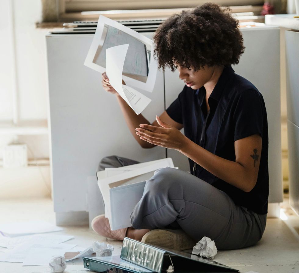 a woman sitting on the floor surrounded by papers and work