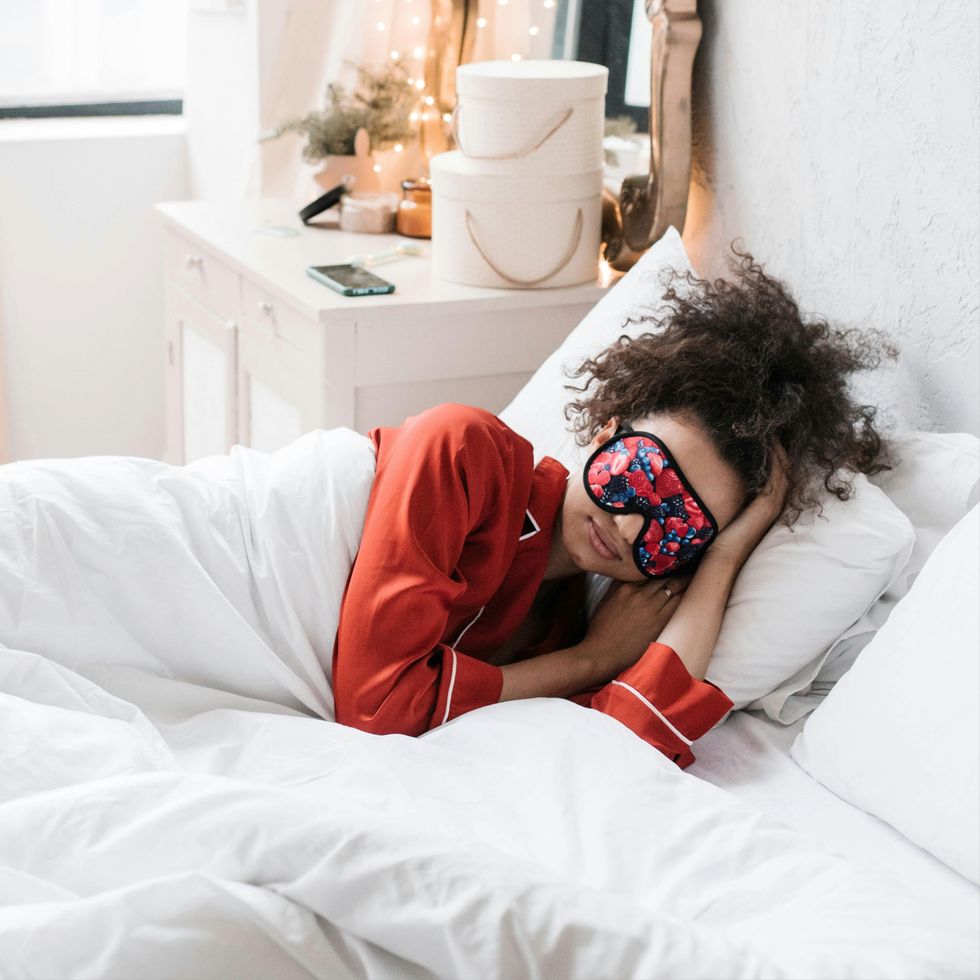 a woman sleeping in red pajamas and a sleep mask
