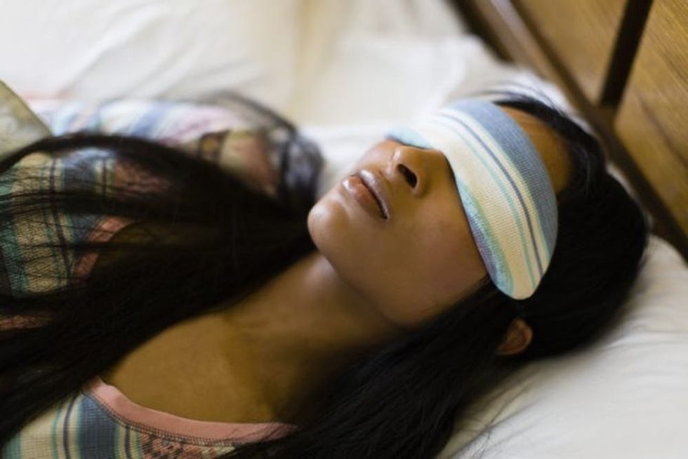 A woman sleeps with a striped mask