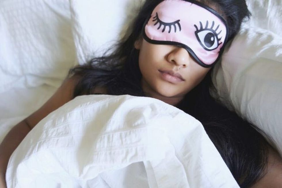 A woman sleeps with a winking pink mask