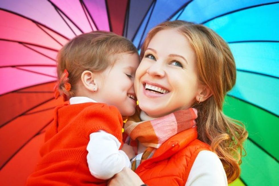 A woman smiles as she holds her happy child