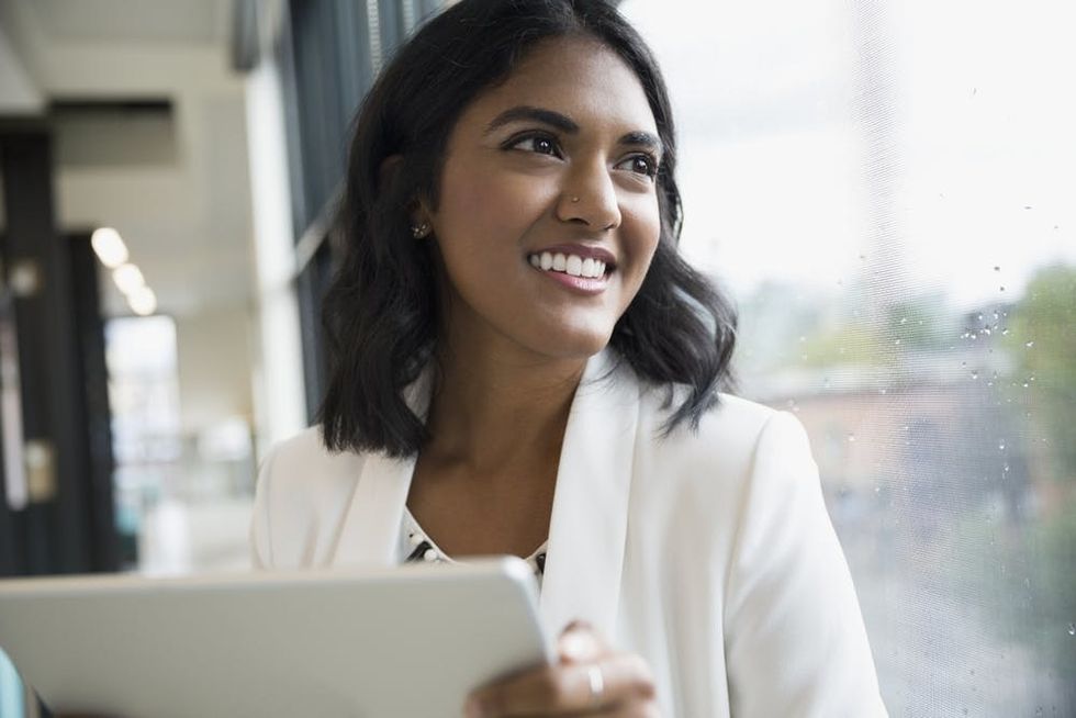A woman smiles as she looks up from a tablet
