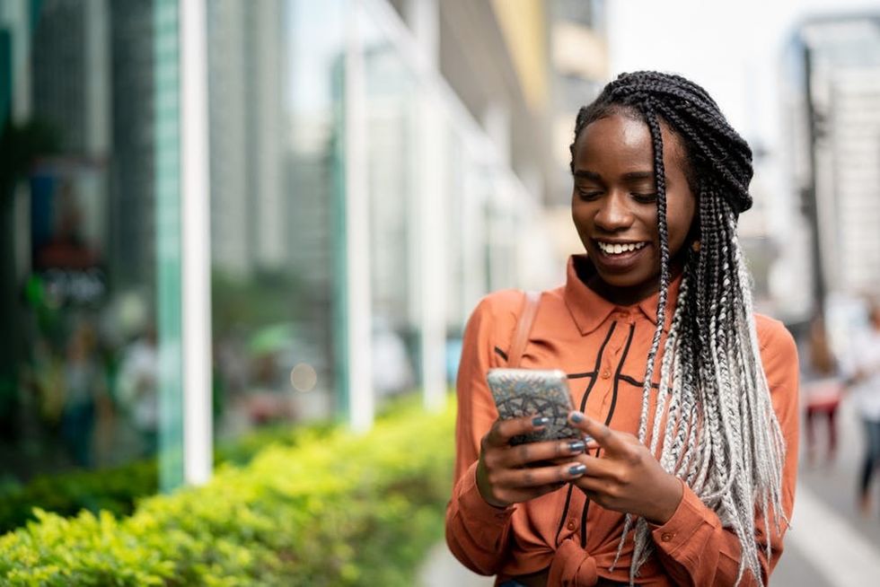 A woman smiles at her phone as she walks down the street
