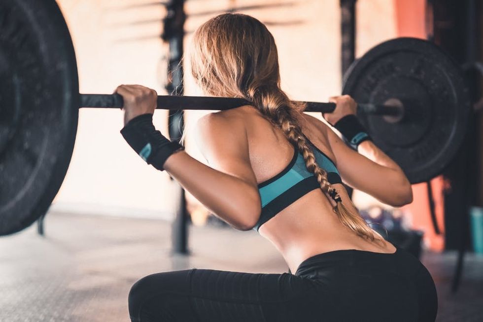 A woman squats with weights at the gym