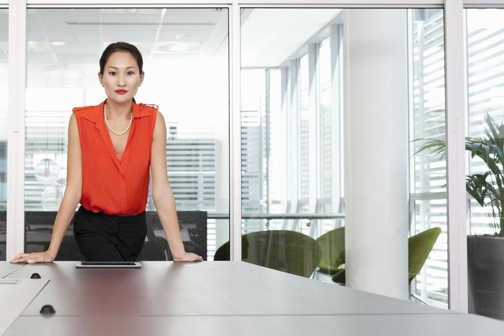A woman stands confidently in front of a conference table