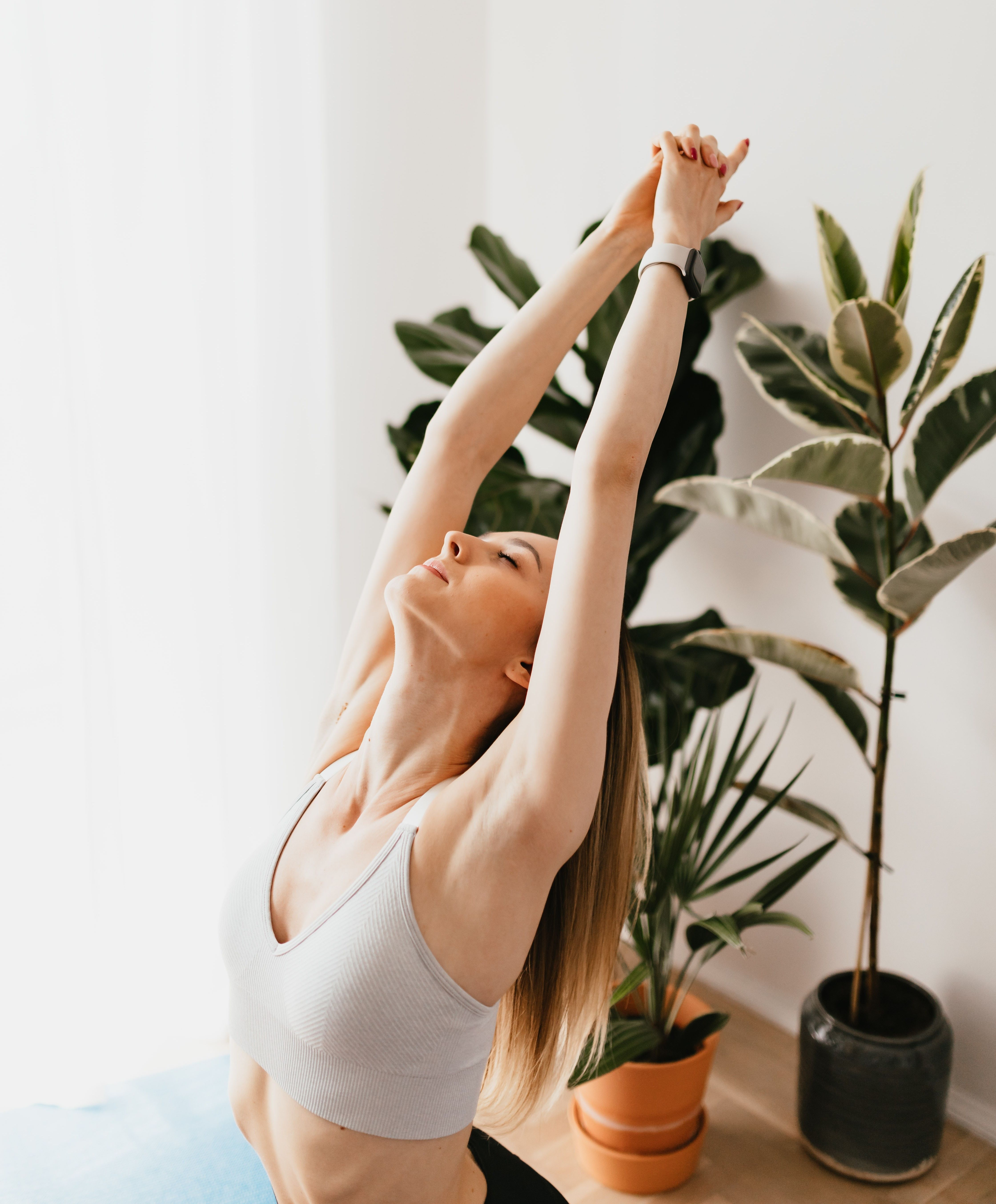 A woman stretches her arms up above her head.