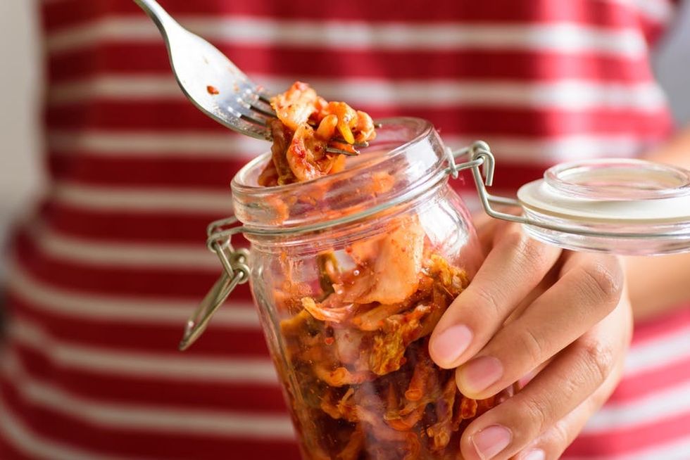 A woman takes kimchi from a jar